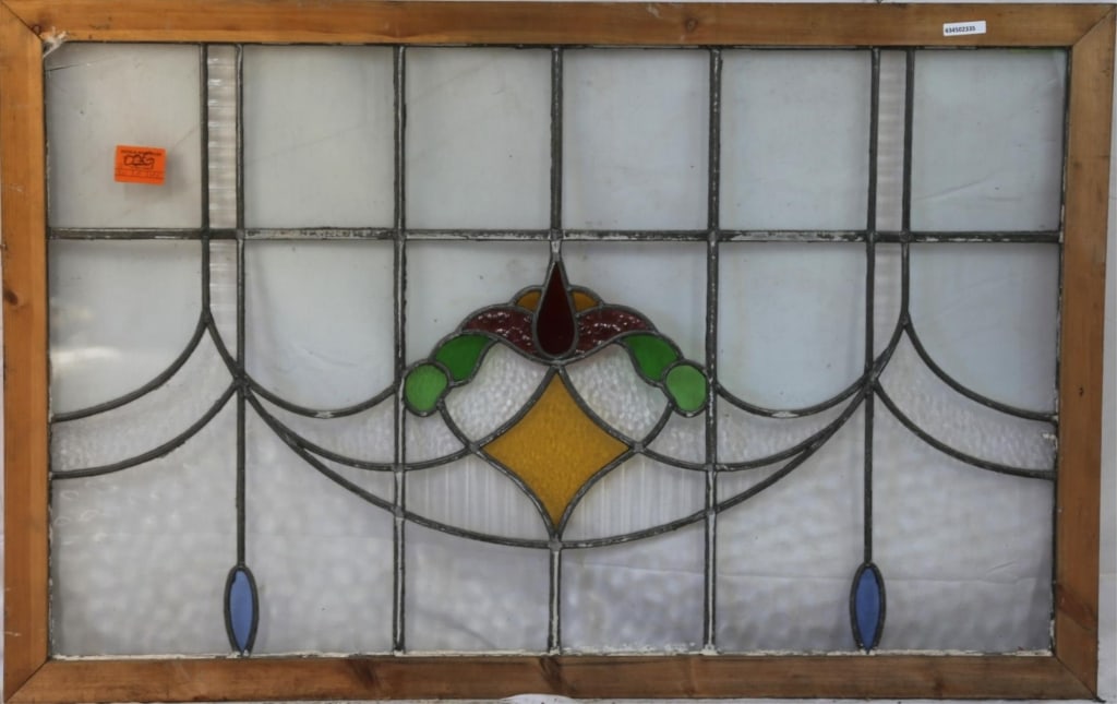 ANTIQUE CONTINENTAL STAINED GLASS PANEL: Antique Continental stained glass panel with an abstract medallion in red, yellow, and green, textured colorless glass panels, and blue stained glass accents. Approximate dimensions: h. 29.5", w. 46"