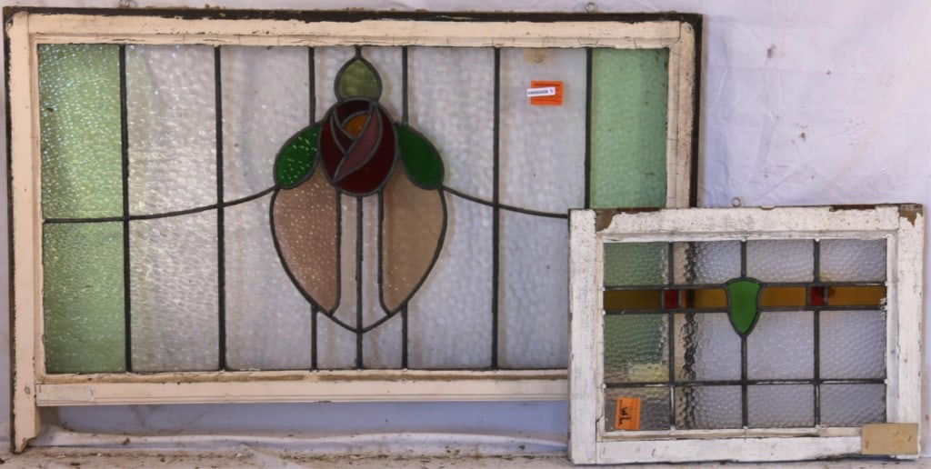 TWO ENGLISH STAINED GLASS PANELS: Two English stained glass panels, one with a heart-shaped medallion with floral detail, and the other with a green shield-form medallion accented in red and amber stained glass. Approximate dimensions