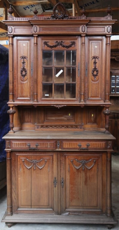 FRENCH ART NOUVEAU OAK VITRINE BUFFET: French Art Nouveau oak vitrine buffet with beveled glass, a wreath and garland pediment, carved appliqués, and carved finials. Approximate dimensions: h. 100", w. 52", d. 24" Disclaimer: This is an o