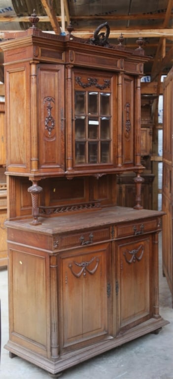 FRENCH ART NOUVEAU OAK VITRINE BUFFET: French Art Nouveau oak vitrine buffet with beveled glass, a wreath and garland pediment, carved appliqués, and carved finials. Approximate dimensions: h. 100", w. 52", d. 24" Disclaimer: This is an o