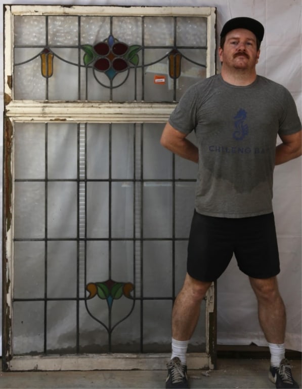 ANTIQUE ENGLISH STAINED GLASS PANEL: Antique English stained glass panel with a floral medallion and symmetrical red and amber accents to the sides. Approximate dimensions: h. 79", w. 40" Disclaimer: This is an online court ordered bankr