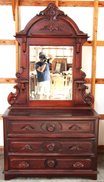 AMERICAN VICTORIAN STYLE MAHOGANY DRESSER: American Victorian style mahogany dresser with beveled mirror, elaborately carved pediment, and hand-carved pulls. Approximate dimensions: h. 94", w. 49", d. 19" Disclaimer: This is an online court or