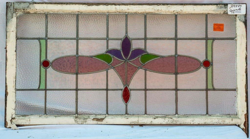 FRENCH ART NOUVEAU STAINED GLASS PANEL: French Art Nouveau stained glass panel with colorless textured leaded glass panels accented with pink, red, purple, and green stained glass details. Approximate dimensions: h. 24", w. 47" Disclaimer: