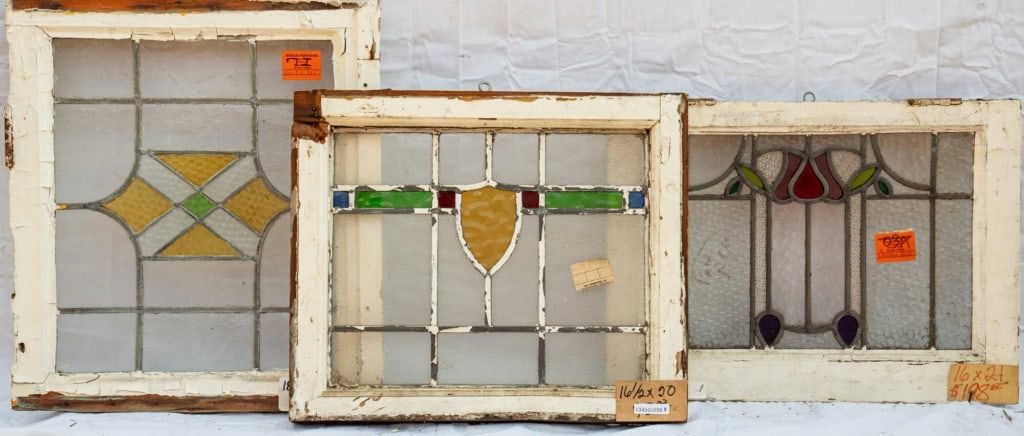 THREE FRENCH STAINED GLASS PANELS: Three French stained glass panels with floral motif and abstract geometric stained glass details. Approximate dimensions: h. 18.5", w. 21.5" Disclaimer: This is an online court ordered bankruptcy sale