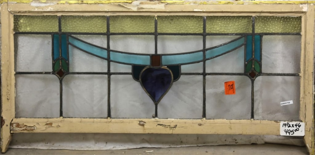 FRENCH ART NOUVEAU STAINED GLASS PANEL: French Art Nouveau stained glass panel with wispy glass heart-shaped floral motif medallion and blue ribbon details. Approximate dimensions: h. 19.5", w. 46" Disclaimer: This is an online court ordere