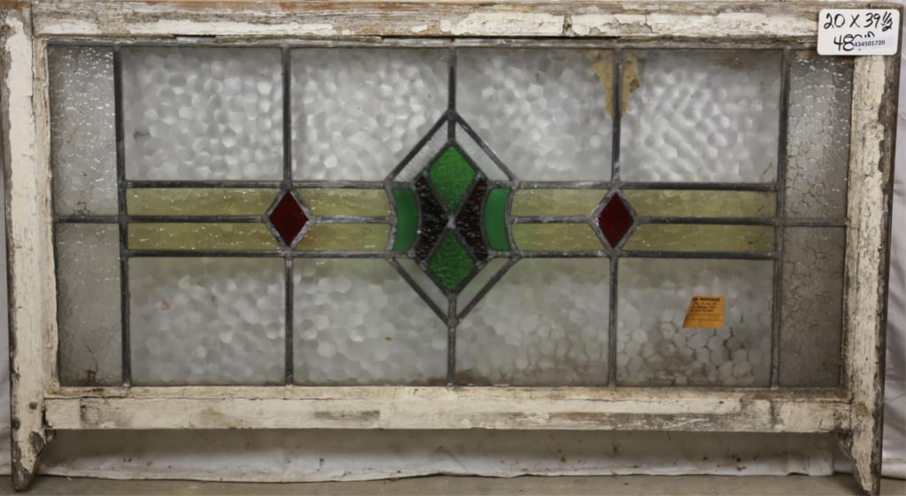ANTIQUE ENGLISH STAINED GLASS PANEL: Antique English stained glass panel with shield medallion and red rhombic accents. Approximate dimensions: h. 20", w. 39.5" Disclaimer: This is an online court ordered bankruptcy sale. Participating b