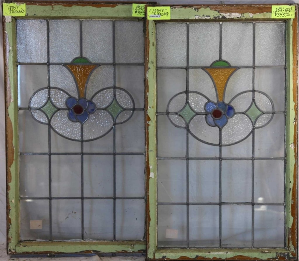 PAIR OF IRISH STAINED GLASS PANELS: Pair of Irish stained glass panels with a floral medallion in blue and red, accented with green and amber stained glass details. Approximate dimensions: h. 42.5", w. 25.5" Disclaimer: This is an onlin