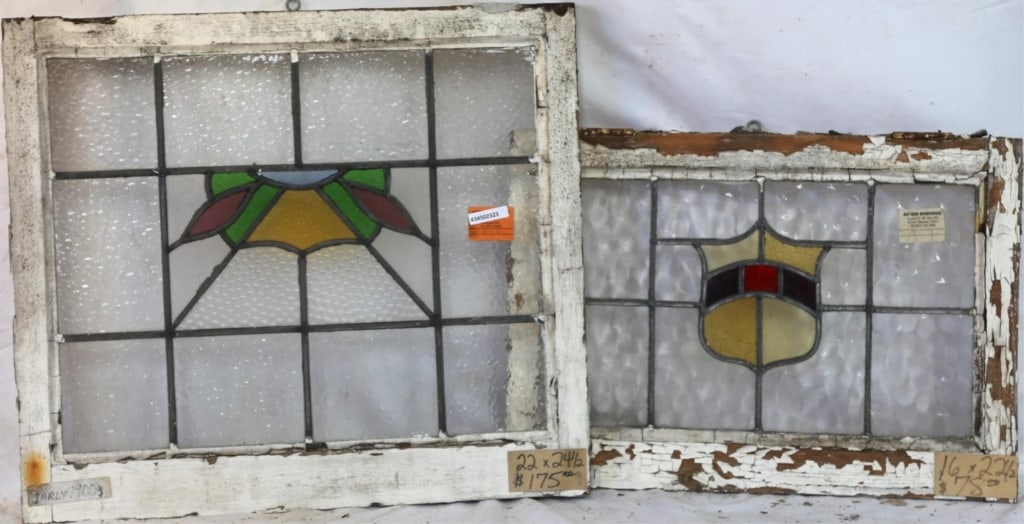 TWO ENGLISH STAINED GLASS PANELS: Two English stained glass panels, one with a shield-form medallion in amber, red, and purple, and the other with an abstract medallion in multicolored stained glass. Approximate dimensions: h. 22", w.