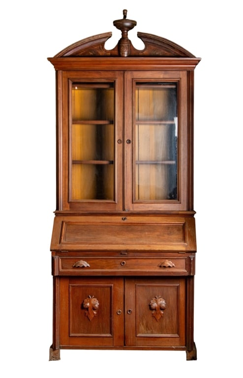 20TH CENTURY WALNUT SLANT FRONT BOOKCASE: 20th century. Two-piece walnut slant front bookcase with broken arch pediment, carved appliques, inset carved panels, felt interior. Approximate dimensions: h. 96", w. 43", d. 23" Disclaimer: Particip