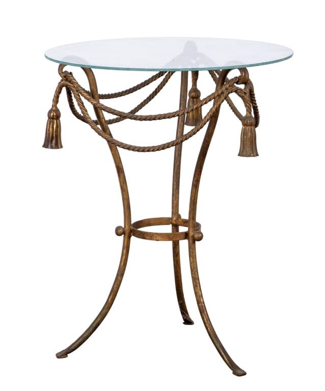 20TH CENTURY REGENCY STYLE ACCENT TABLE: 20th century. Regency style accent table with glass top and painted metal base with tassel details. Approximate dimensions: h. 22", dia. 17.5" Disclaimer: Participating bidders must have a credit