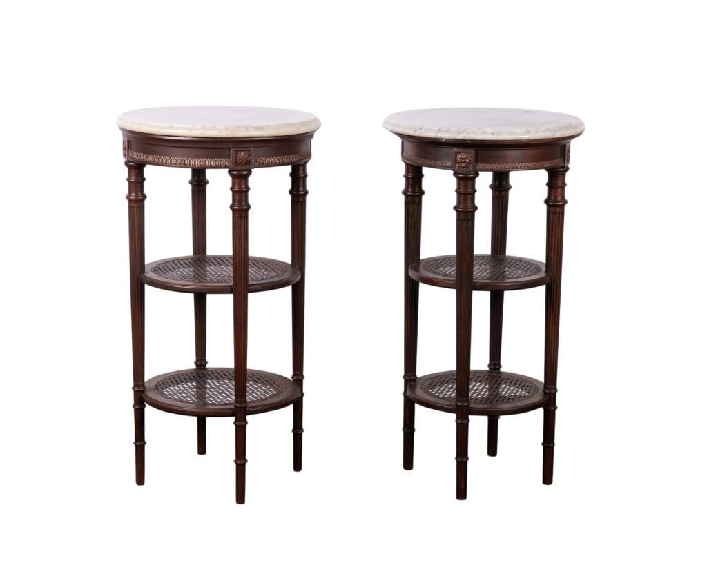 PAIR OF TWO-TIER MARBLE TOP LAMP TABLES: Pair of two-tier marble top lamp tables with turned and fluted legs, and caned shelves. Approximate dimensions: h. 30", dia. 16" Disclaimer: Participating bidders must have a credit card on file with