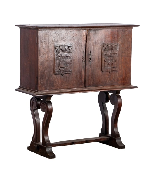 JACOBEAN STYLE CARVED CABINET: stretcher base, carved legs, coar of arms carved appliques Approximate dimensions: h. 44", w. 41", d. 15.5" Disclaimer: Participating bidders must have a credit card on file with LiveAuctioneers in or