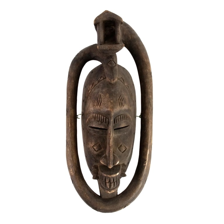 AFRICAN IVORY COAST BAULE HAND CARVED WOOD MASK: African Ivory Coast or Cote D'ivoire hand-carved wood mask depicting a grimacing face with a snake coiled around it. Approximate dimensions: h. 17", w. 7", d. 4.5" Disclaimer: Participating bidders