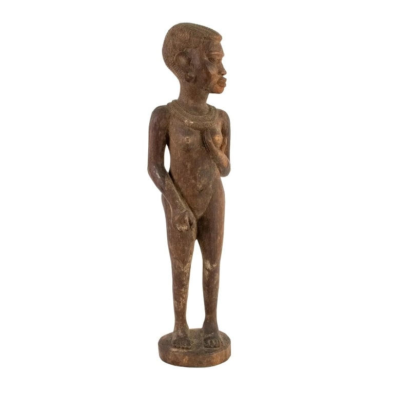 AFRICAN HAND CARVED WOOD FIGURAL NUDE STATUE: African hand-carved wood figural statue depicting a nude tribal woman holding on of her breasts. Approximate dimensions: h. 15.25", w. 4", d. 2.5" Disclaimer: Participating bidders must have a credit