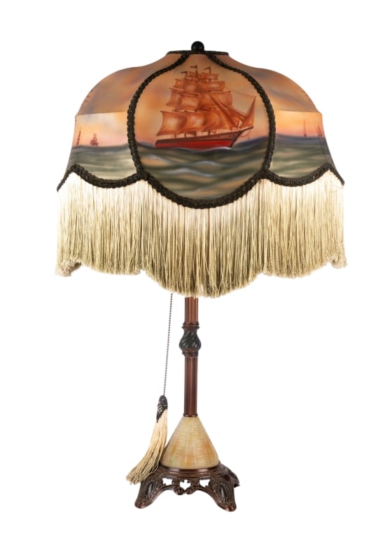 PARLOR LAMP WITH HAND-PAINTED SHIP SCENE & TASSELS: Parlor lamp with hand-painted ship scene and tassles. Approximate dimensions: h. 33", w. 21", d. 15" Disclaimer: Participating bidders must have a credit card on file with LiveAuctioneers in order for