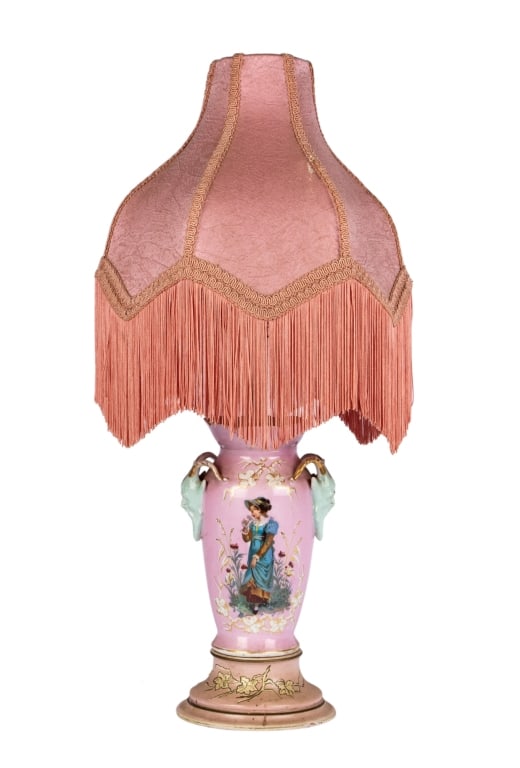 VICTORIAN PINK MAJOLICA FIGURAL LAMP: Victorian pink Majolica figural lamp with pink shade and fringe. Approximate dimensions: h. 19", w. 6.5", d. 6.5" Disclaimer: Participating bidders must have a credit card on file with