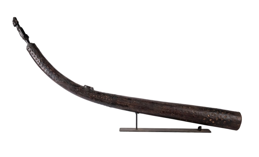 AFRICAN CARVED WOOD SCULPTURE: African carved wood sculpture with figure of a man at a tip, carving throughout. Approximate dimensions: h. 26", w. 58", d. 5" Disclaimer: Participating bidders must have a credit card on file with
