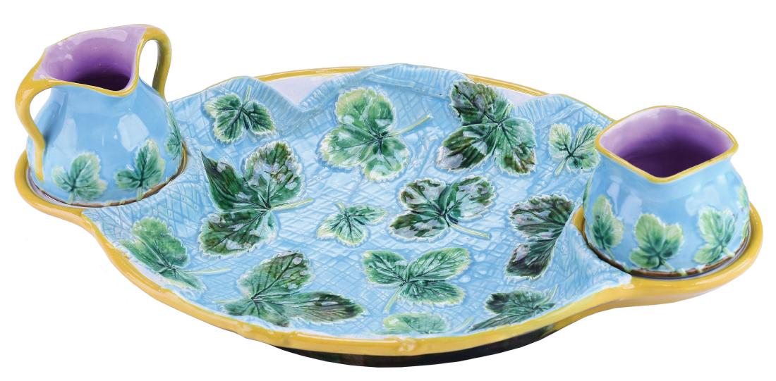 George Jones Majolica Napkin Strawberry Dish: c.1875, the oval dish decorated with a turquoise napkin scattered with strawberry leaves, a receptacle ring at each end, the turquoise cream and sugar pots decorated with strawberry leaves, 14". Curat