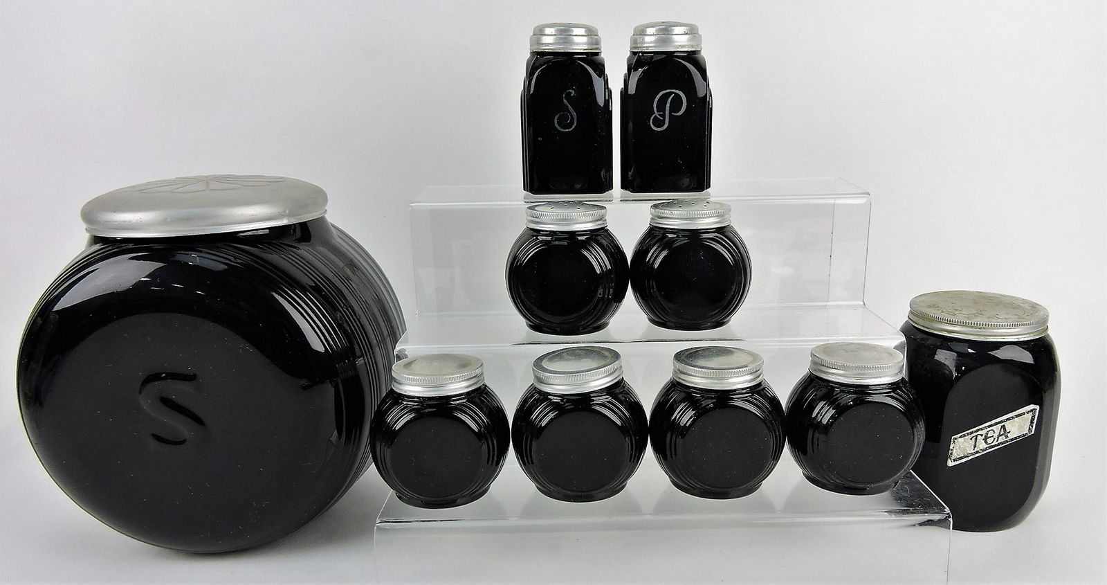 Black milk glass Sellers kitchen: cabinet cookie/sugar jar with embossed "S" and tin daisy lid, tea canister, 2 pair shakers, 4 spice jars