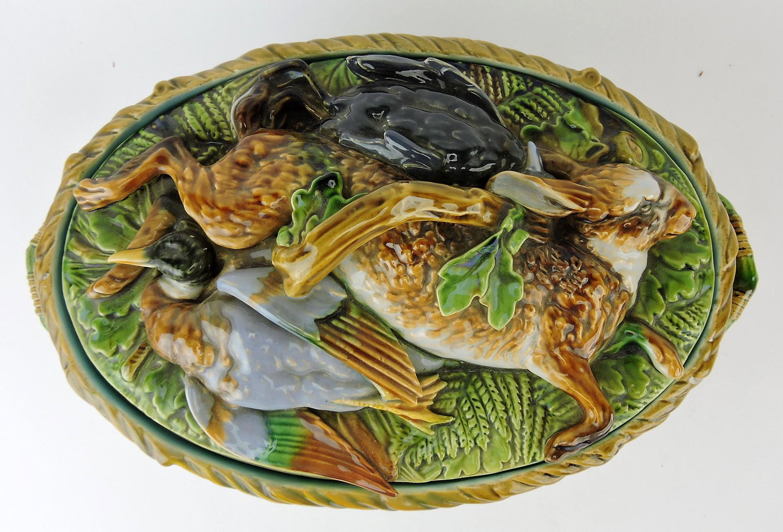 Minton majolica game dish with: rabbit, duck, and quail on cover with wicker base, includes liner, hairline and hairline repair to base, 13 1/2"