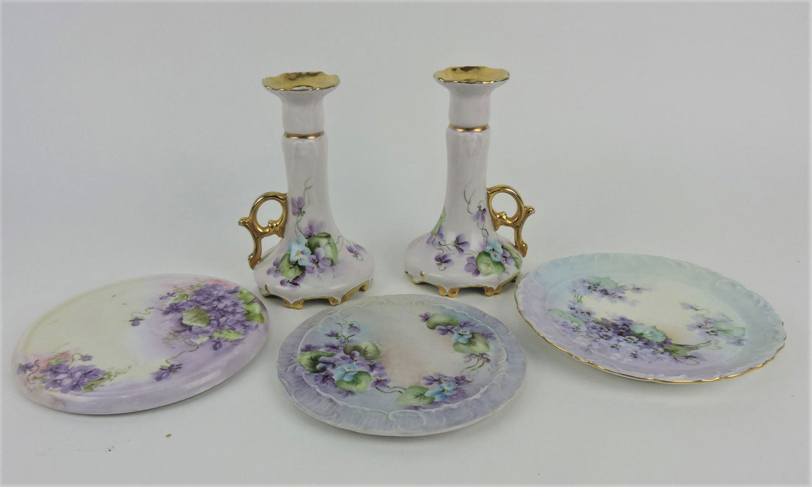 Limoge pair of candle sticks and 3: trivets with violets