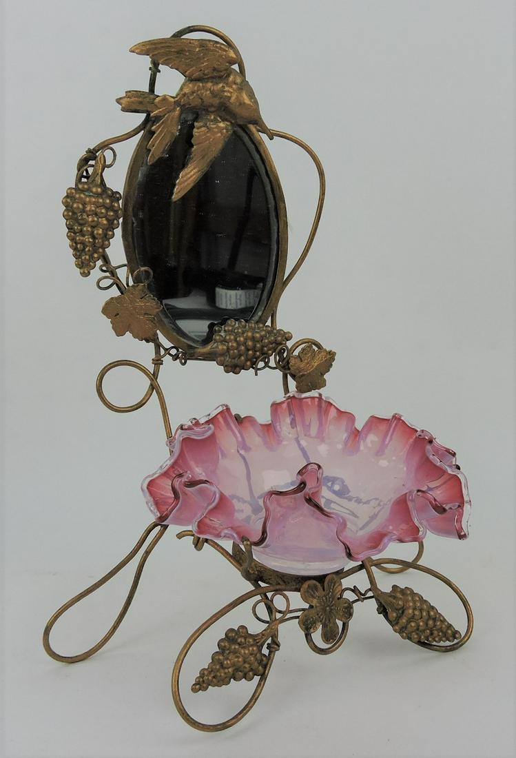 Small dresser mirror with cranberry: opalescent bowl mounted in brass/bronze ormolu frame with bird, grapes, and vine, 10 1/2"