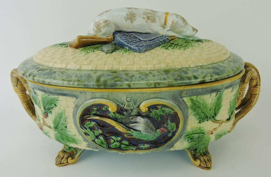 Large Minton Gun Dog majolica tureen: shape no. 964, modeled as an oval cream ground basket and cover, holly leaves to the sides, the holly branches forming the handles of each end, an oval cartouche to each side, one depicting a running