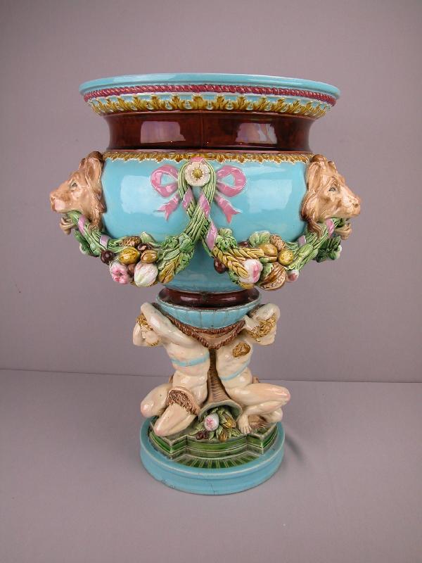 MINTON majolica pedestal jardiniere with three : MINTON majolica pedestal jardiniere with three lion heads and garland drapes of muts and fruit all supported by three men seperated by cornucopias overflowing with fruit, early staple repairs, loss of