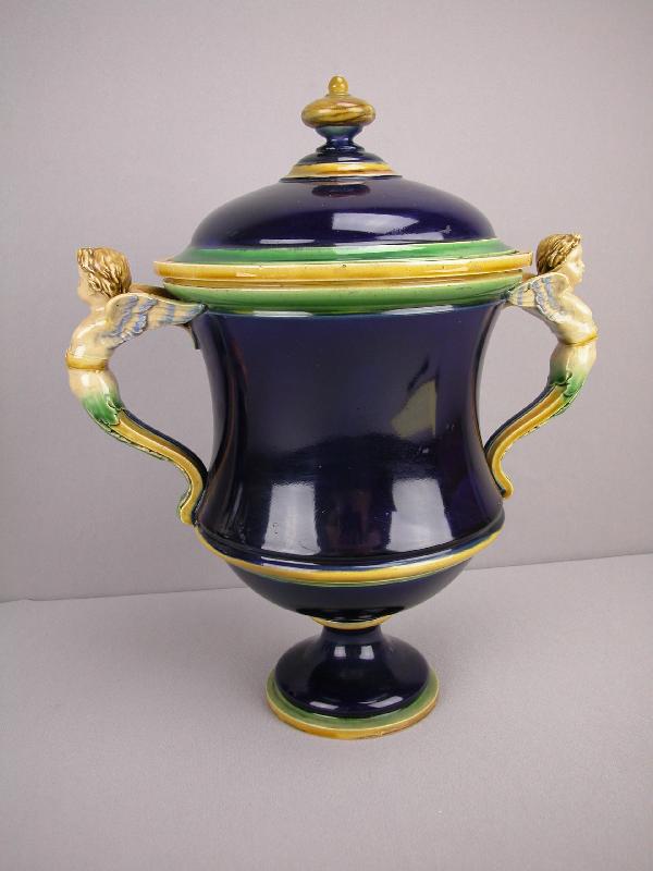 MINTON cobalt majolica urn with winged putti han: MINTON cobalt majolica urn with winged putti handles, professional repair to lid, 13 1/2"h, 11 1/2"w