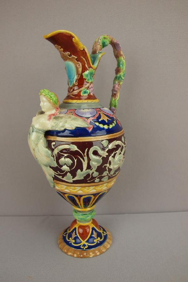 MINTON majolica wine ewer with winged lady at s: MINTON majolica wine ewer with winged lady at spout, grapes, shells, snakes and birds in relief, early staple repair to handle and repair to spout, 14"h