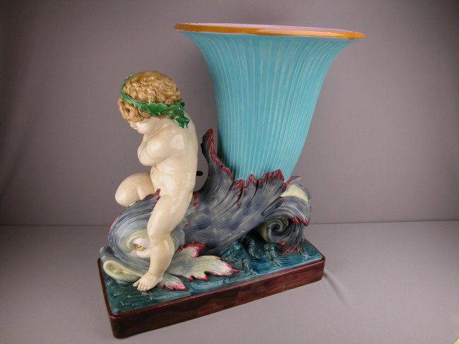 MINTON monumental majolica floor jardiniere in th: MINTON monumental majolica floor jardiniere in the form of a cherub riding a dolphin terminating in a turquoise trumpet shaped flower vase, designed by Hughes Protat, shape no. 808, professional repai
