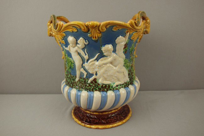 MINTON majolica Campaniform wine cooler with group: MINTON majolica Campaniform wine cooler with group of Bacchanalian figures on each side and goat's head handles on periwinkle/gray ground, 10"