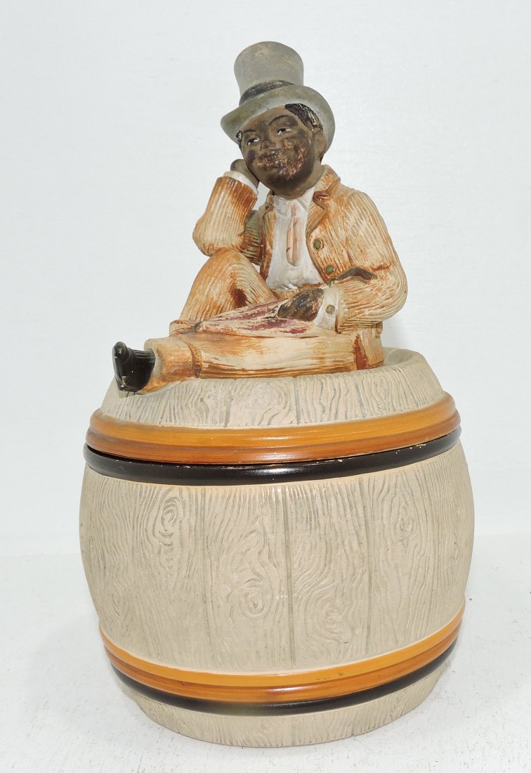Black Americana terra cotta humidor: of man atop a barrel, 9", minor nick to lid rim, signed J.M.