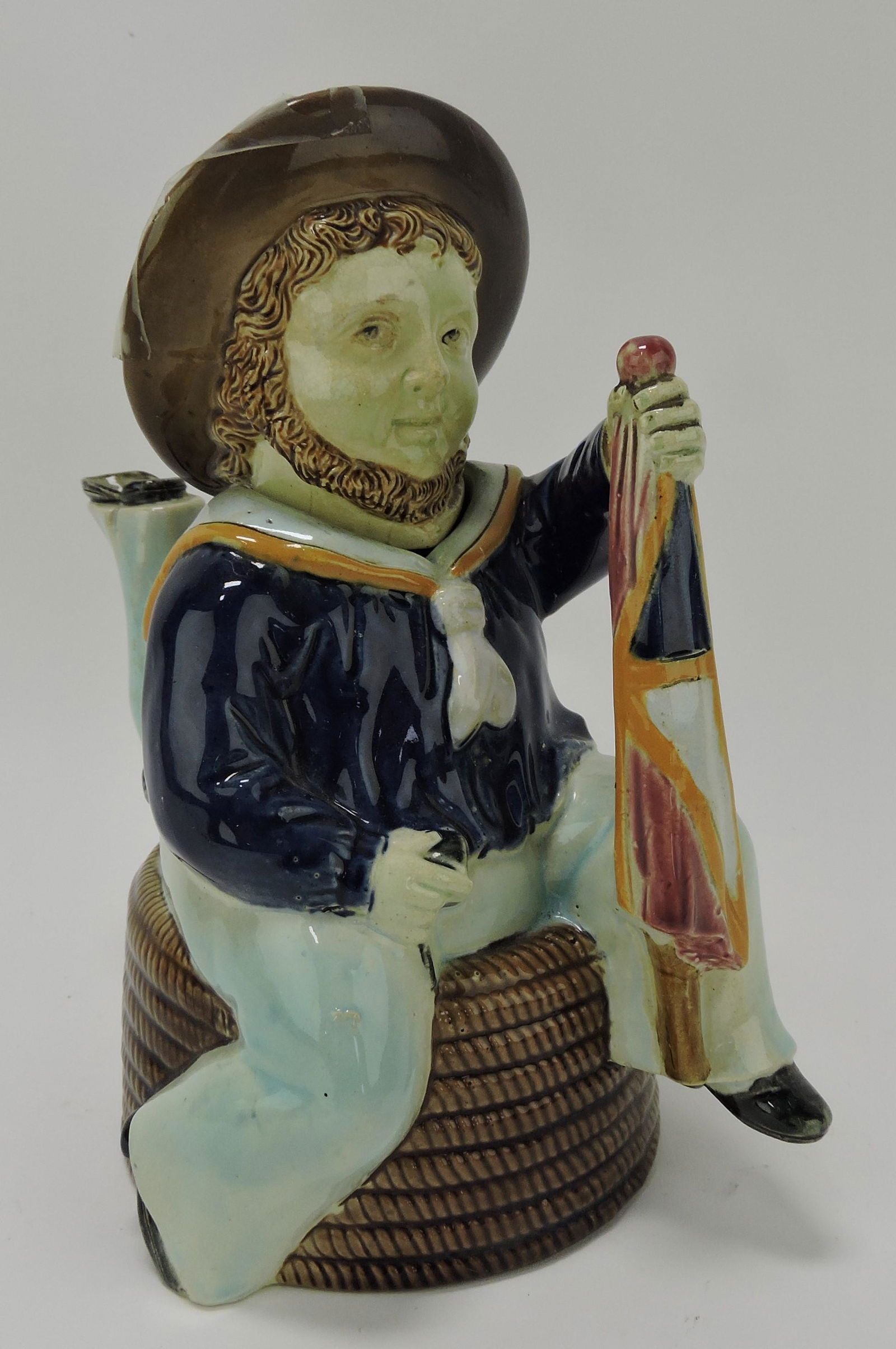 Holdcroft majolica Isle of Man teapot with: sailor atop a coil of rope holding a flag, damage to hat rim, 8"
