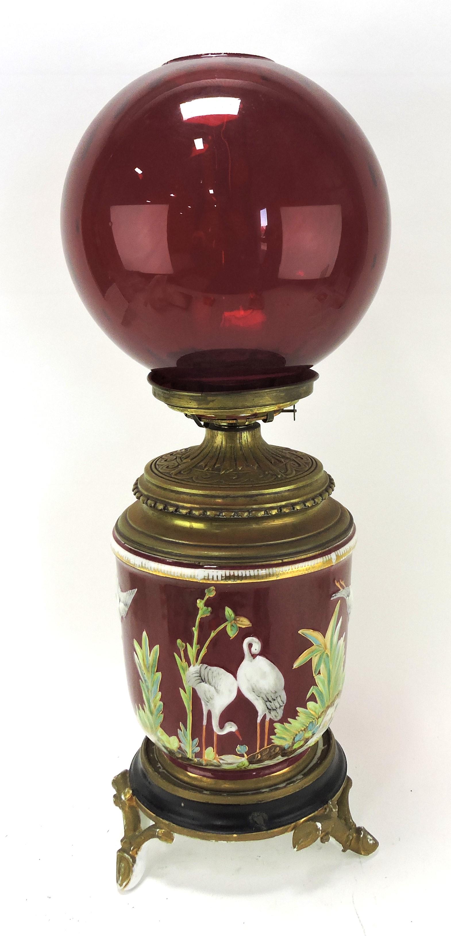 Porcelain oil lamp with storks in: marsh, brass font and ruby red shade, 26"