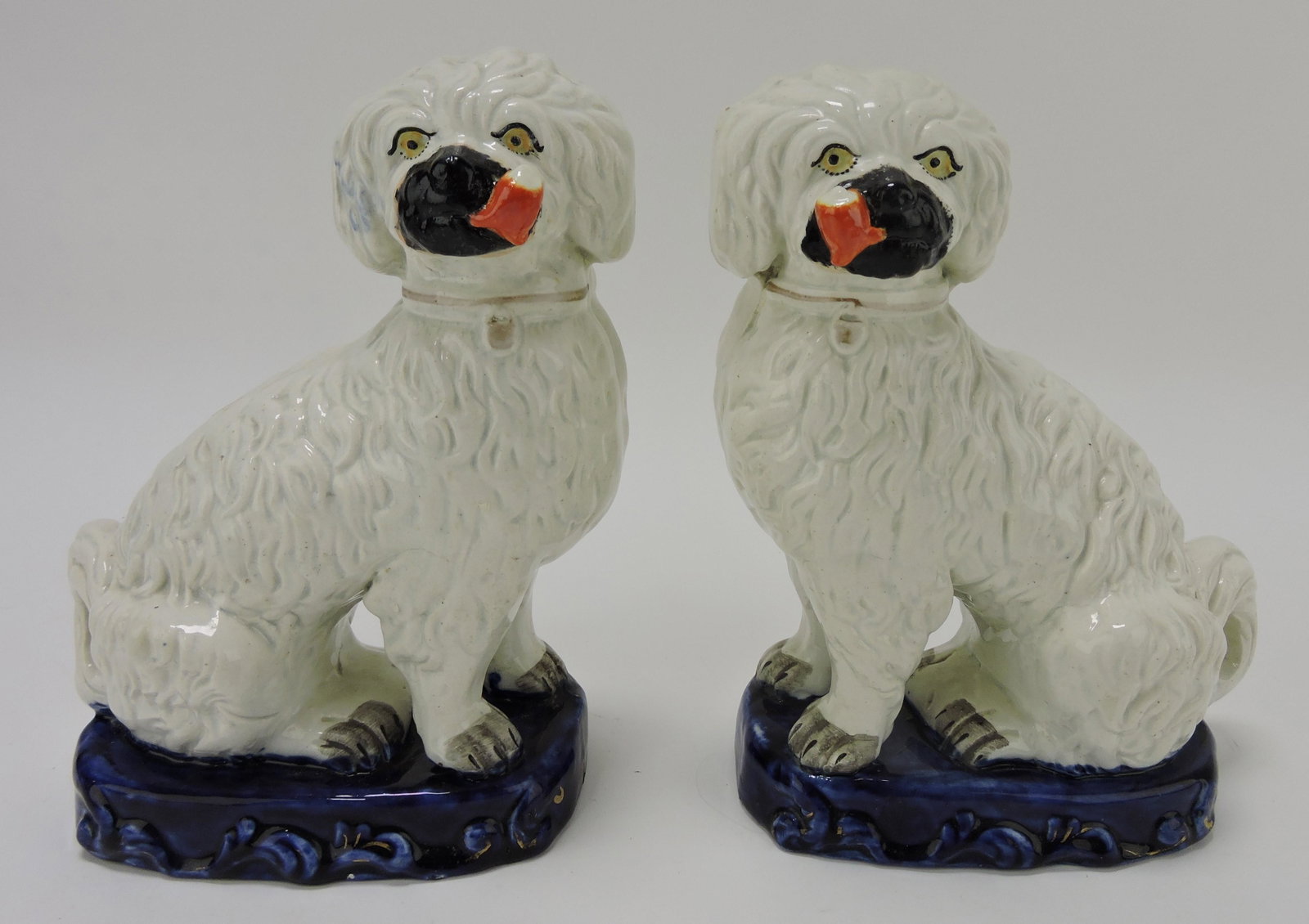 Staffordshire pair of dogs with smoking: pipes on oval cobalt plinth, professional repair to pipes and head of one dog, firing line to tail, 9"