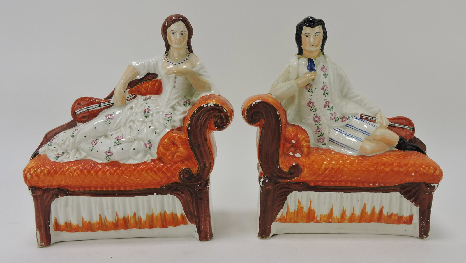 Staffordshire pair of figures of: recumbent man (head and arm repair) and lady (hand repairs) on sofa, 8"h, 8 1/2"l