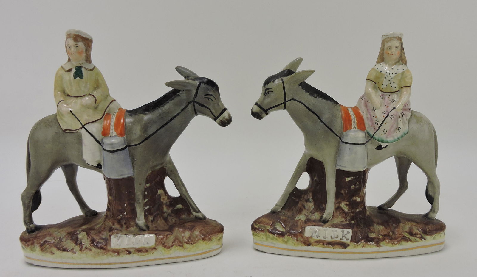 Staffordshire pair of donkeys with boy: and girl, inscribed 'Milk', 7 1/2", ear repair