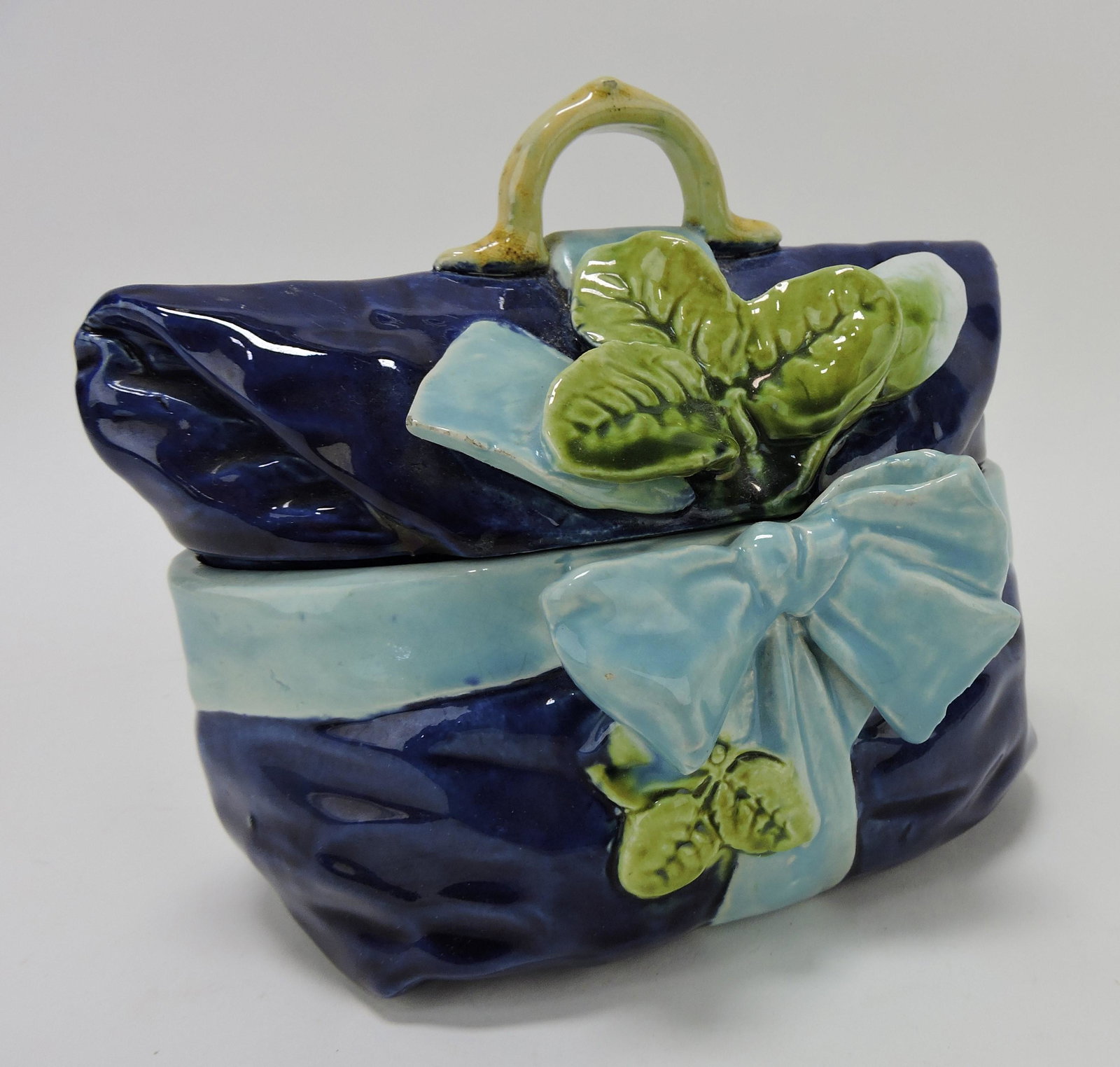 Majolica cobalt covered box in the form: of a purse with turquoise ribbon and bow with flower bud, 6 1/2"w, 5"h
