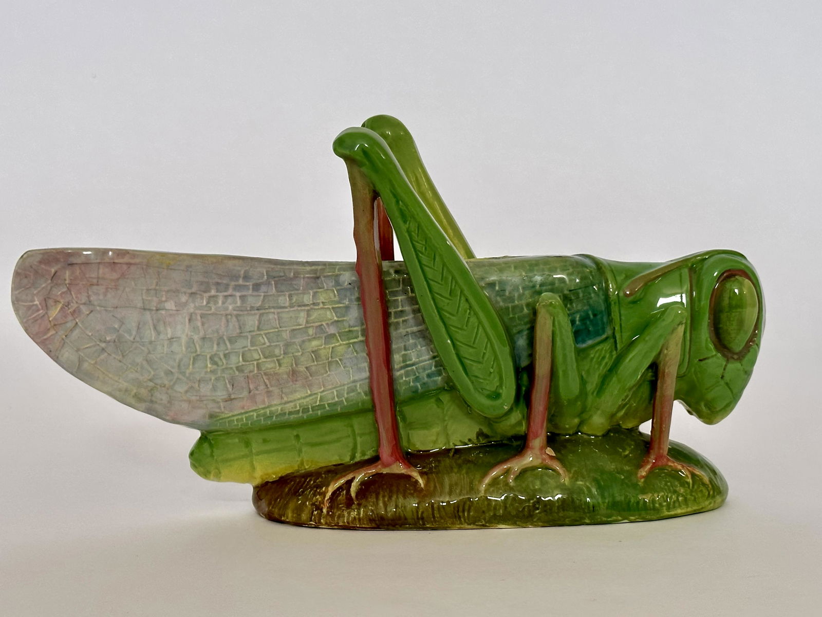 A very beautiful Jerome Massier: Vallauris French majolica figural grasshopper on an oval base naturalistically modeled and enriched in shades of yellow, grey, green and pink, c1890. Very nice color and detail. 5 3/4”h, 11̶