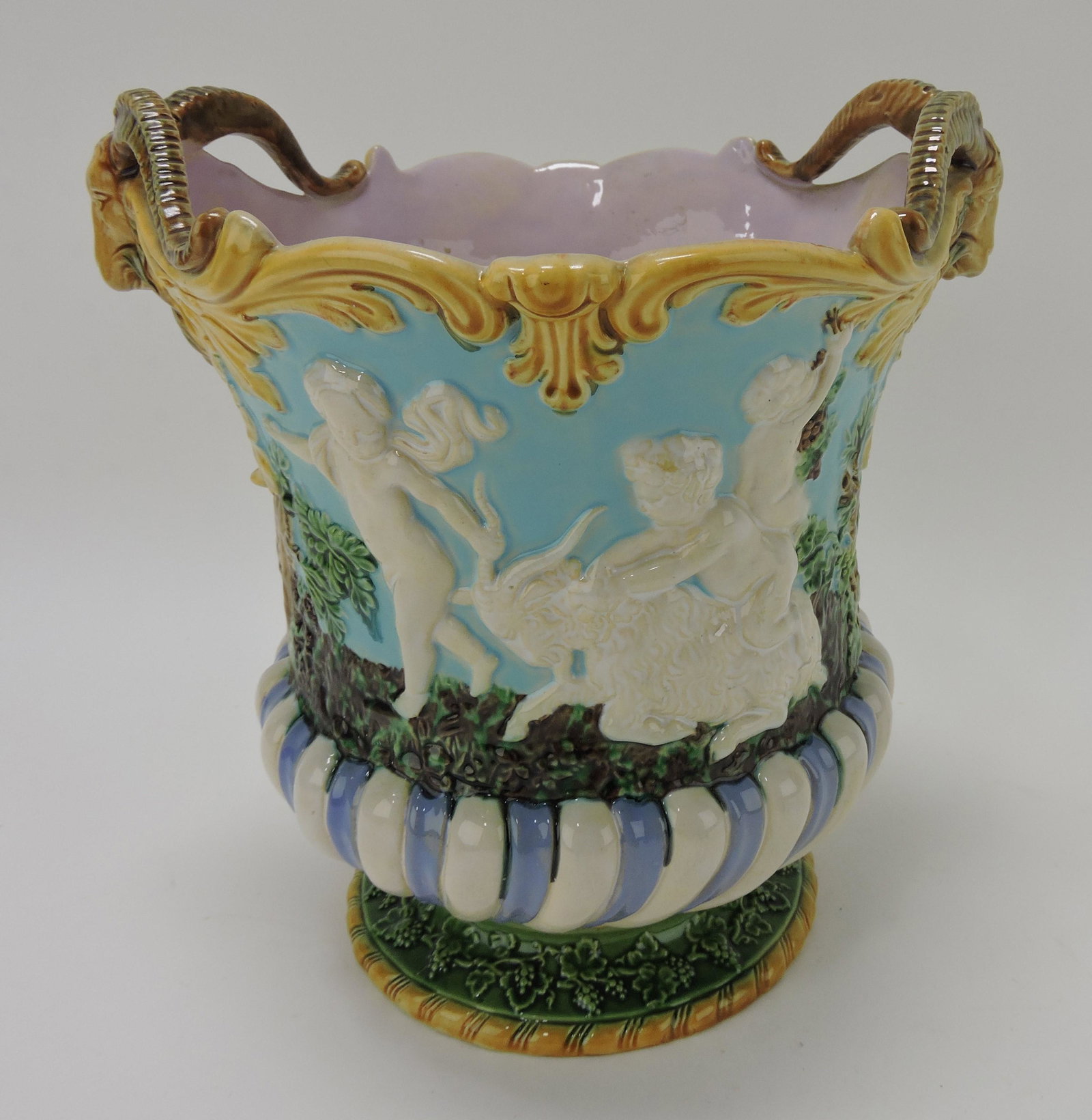 Minton majolica wine cooler with group: of Bacchanalian figures in relief on each side and goat head handles with turquoise ground, 10"h, 9 1/2"w