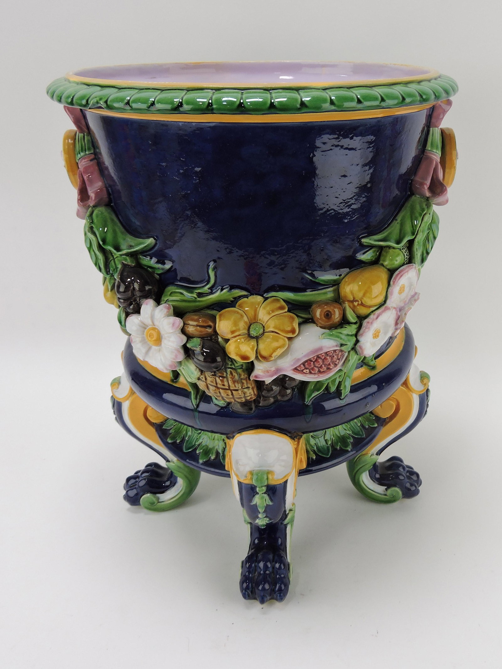 Minton majolica floral and fruit swag: wine cooler with cobalt ground with two swags of fruit, blossoms and leaves strung from two rosettes tied with pink ribbon on four cabriole legs, paw feet, 16"h, 12"w