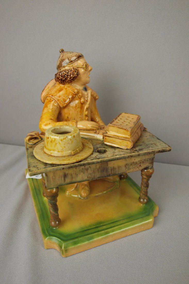 Portugal majolica figural inkwell or deskstand in : Portugal majolica figural inkwell or deskstand in the form of a man with glasses seated at desk with books, top hat and cigar, rare form, professional repair to base rim, 7 1/2"h