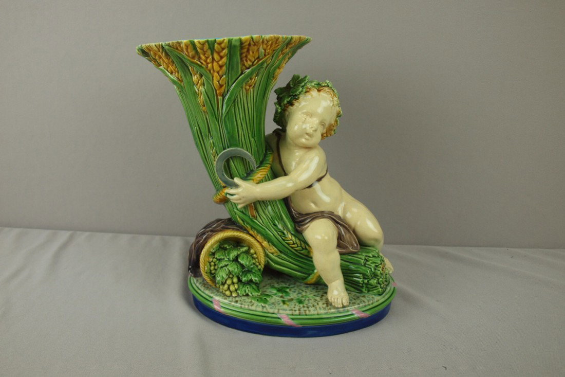 MINTON majolica figural vase in the form of a putt: MINTON majolica figural vase in the form of a putti holding a cornucopia of wheat with a barrel of grapes, 11", shape no. 1198, professional rim repair