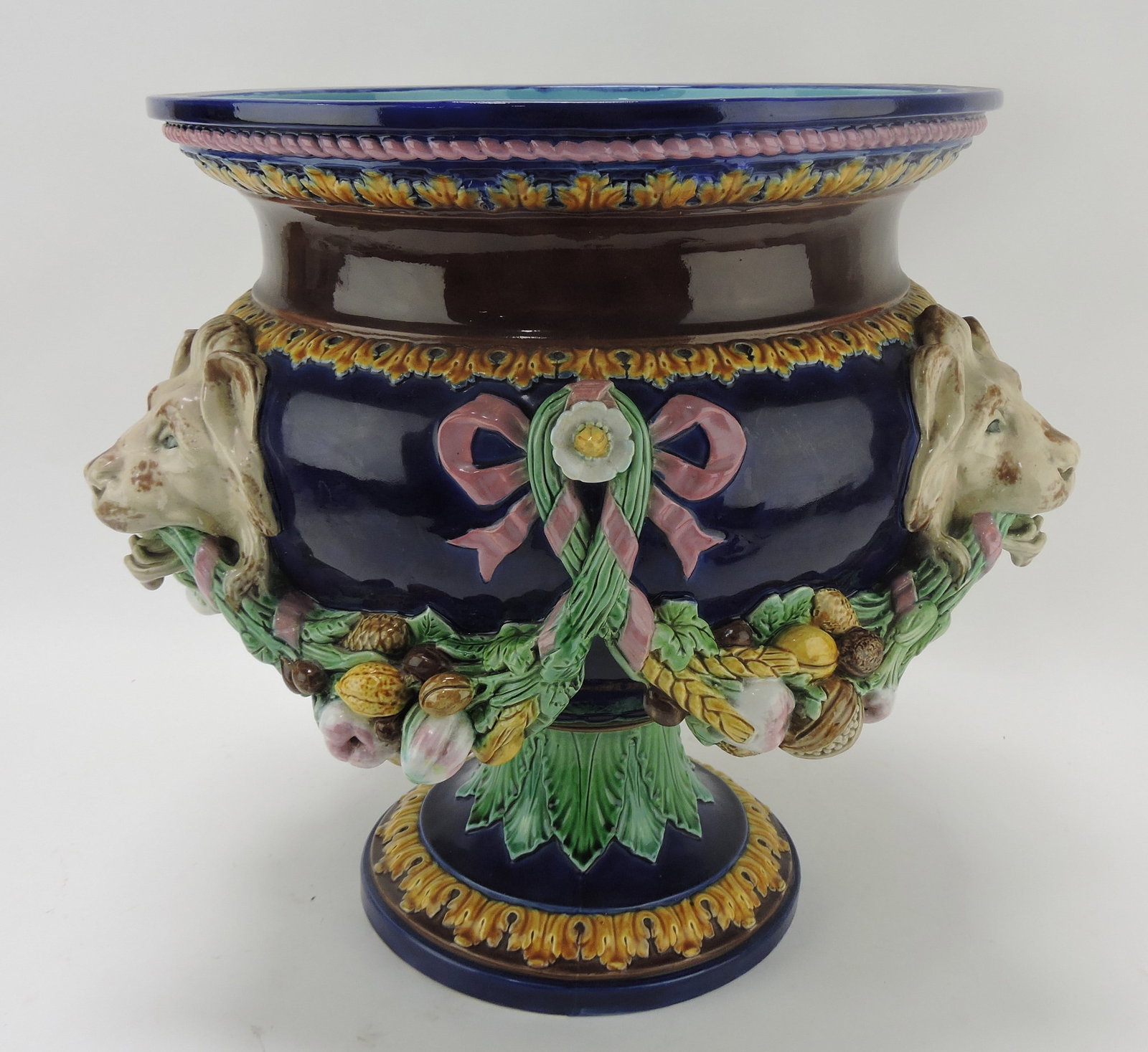 Minton majolica cobalt jardiniere with: lion masks supporting garlands of nuts and fruit with pink ribbons, 14 1/2"h, 15"w. Sue & Harry Thurmon Collection