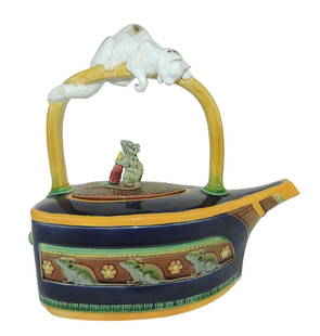 An Iconic Minton Majolica Flat Iron: Teapot c.1875, modeled as a flat iron with a frieze of mice to the sides and a large white cat wrapped around the handle looking down at a mouse holding a carrot to form the handle of the lid. An exam