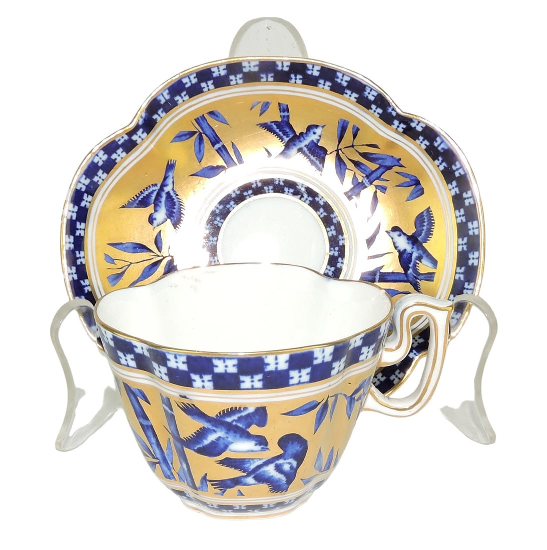 Coalport Porcelain Aesthetic Movement: Japanese Grove Cup and Saucer c.1880, the white ground body with blue transfer against 22ct gilded background Catalogued and curated by Nicolaus Boston