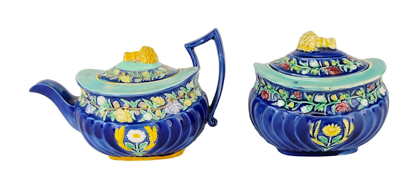Rare Wedgwood Majolica Harvest: Teapot and Sugar bowl c.1875, both with oval segmented bodies, with a central flower between wheat sheaves below a deep collar of trailing blossoms, the covers, with collar of trailing blossoms and bu