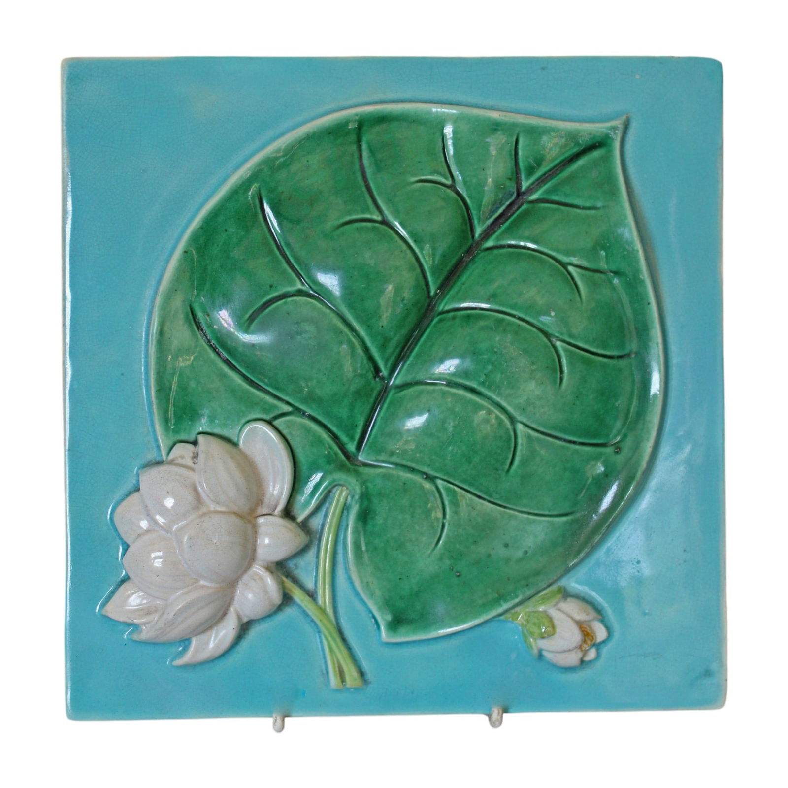 A George Jones majolica water lily tile: modelled in relief, turquoise ground, 8” square