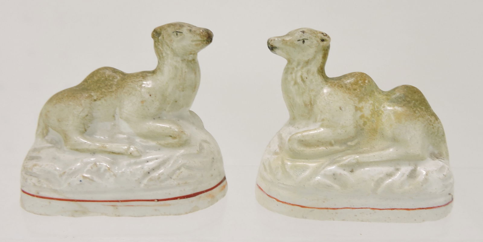 Staffordshire pair of recumbent camels,: 3", hairline to left camel